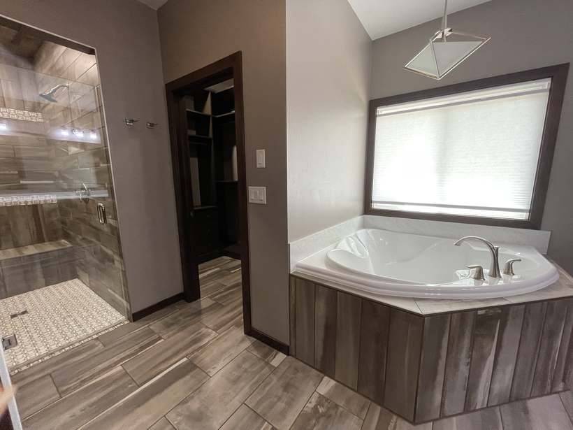 The corner soaking tub with wood panel surround