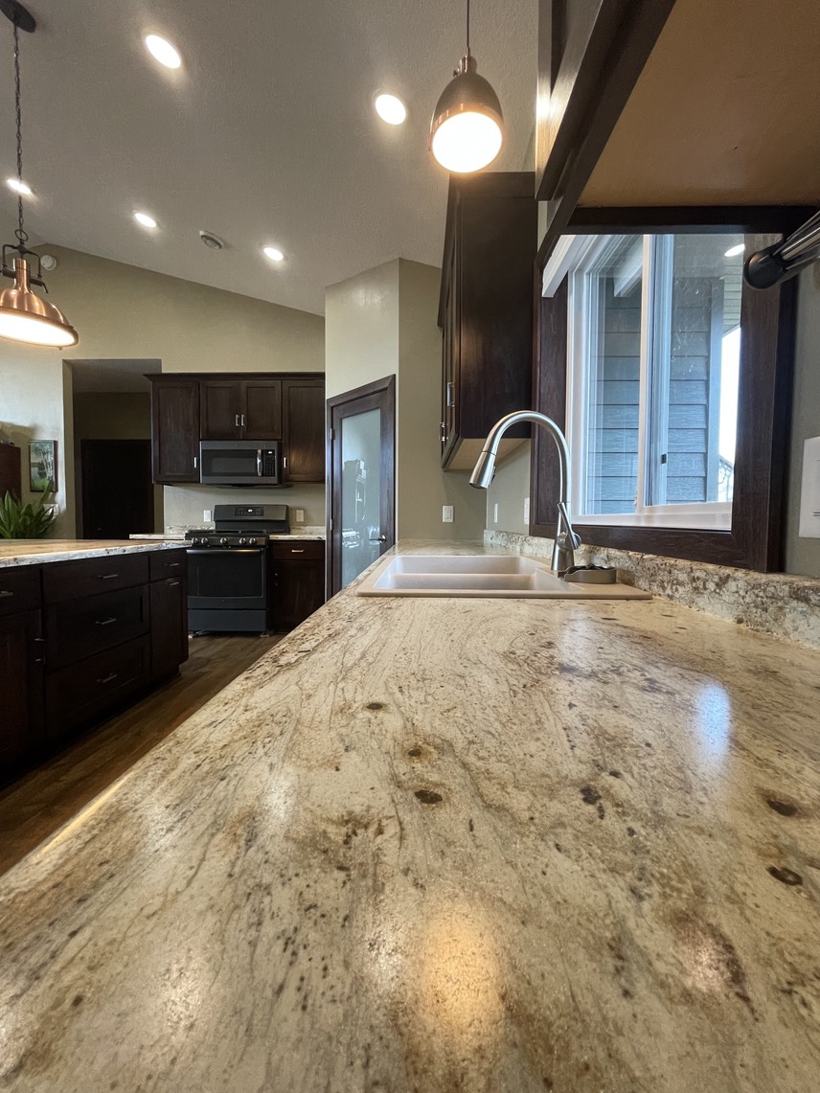 Kitchen in St. Cloud, MN with laminate countertops, dark wood cabinets, and pendant lights
