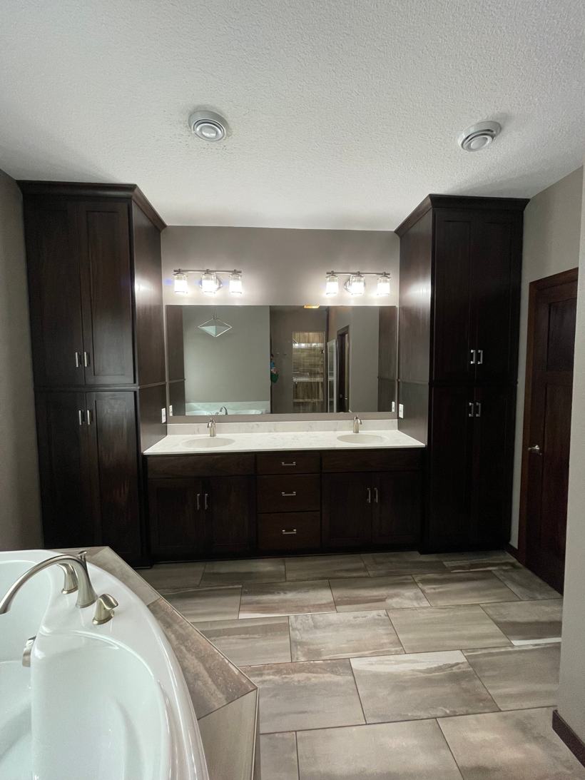 Master bathroom in Rockville, MN with a double vanity, tall custom cabinets, and a soaking tub