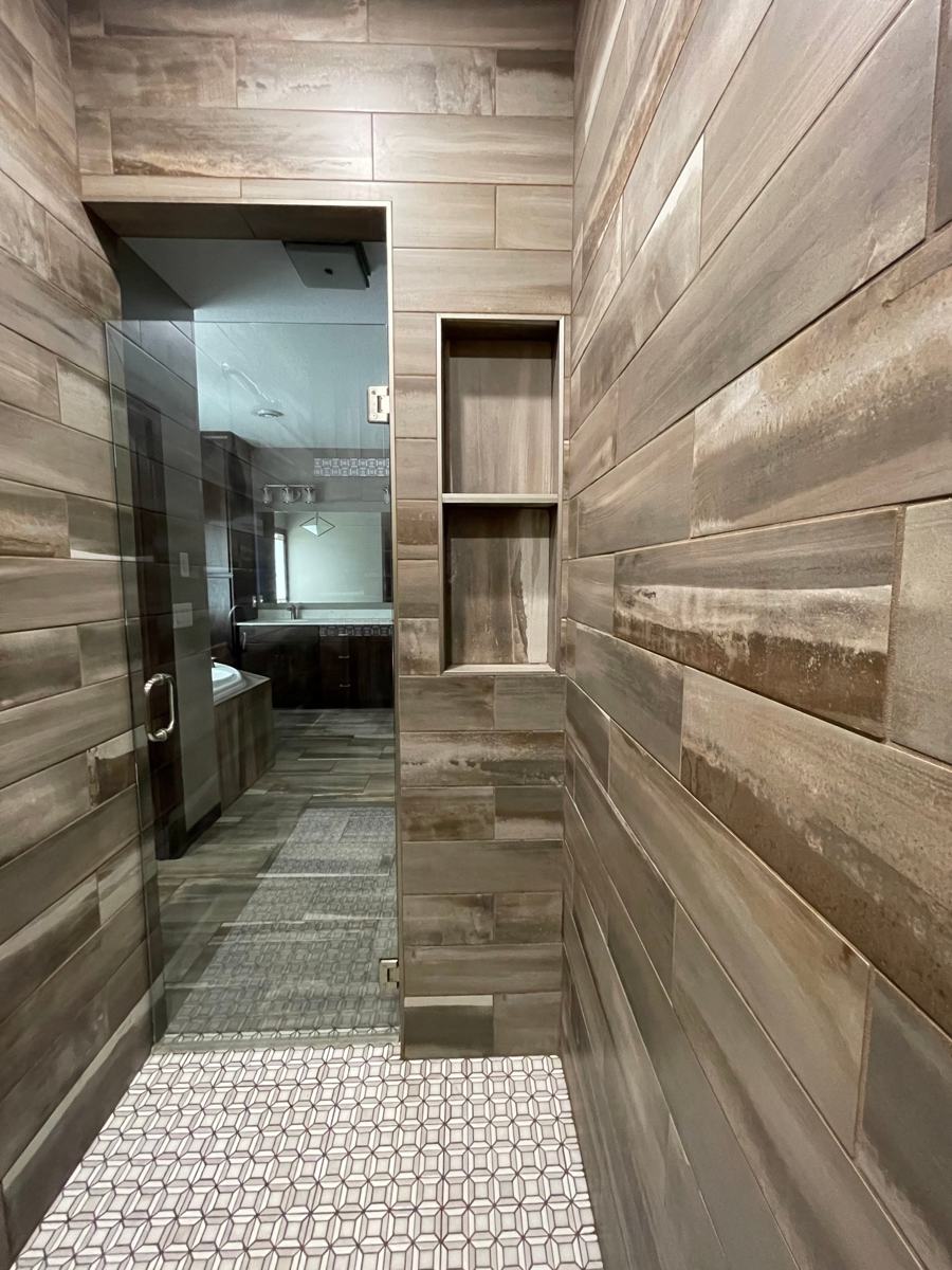 Walk-in tile shower with a built-in niche and mosaic floor in a new construction bathroom in Rockville, MN